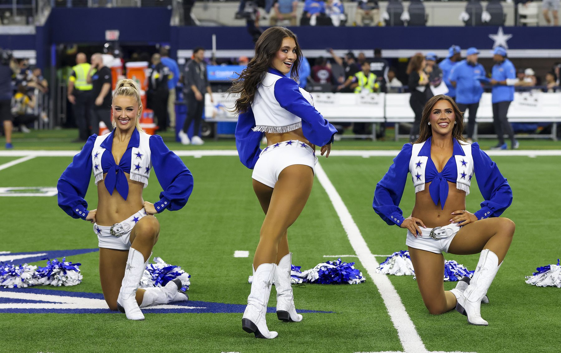 Three Dallas Cowboys Cheerleaders posing on the field