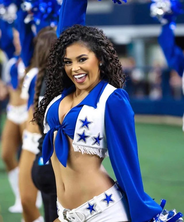Dallas Cowboys Cheerleader smiling mid-routine on the field